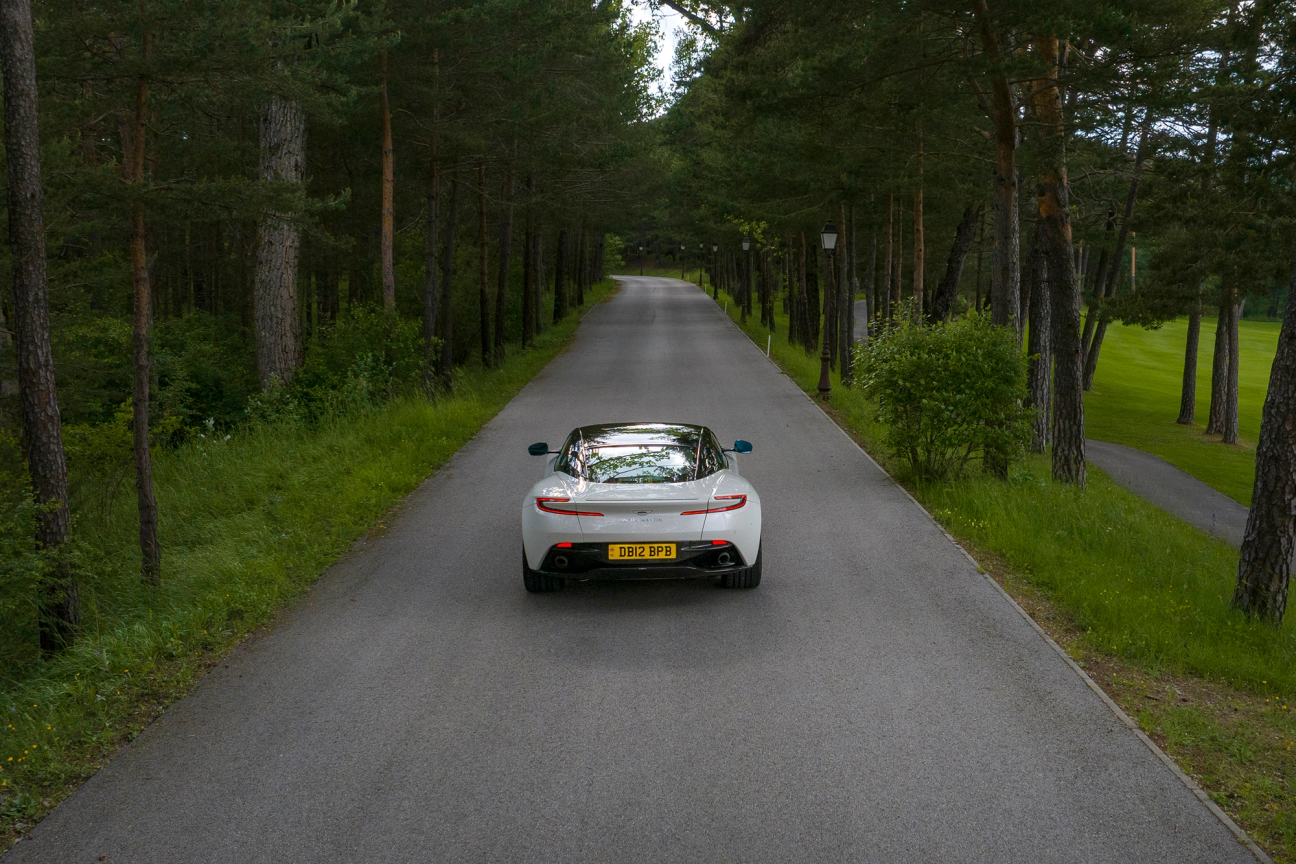 White Aston Martin DB12 driving on the road