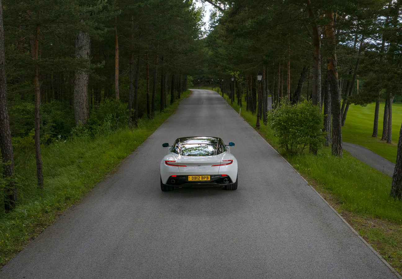 White Aston Martin DB12 driving on the road