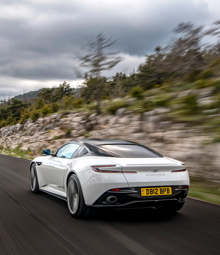 White Aston Martin DB12 driving on the road