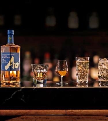 A bottle of Japanese whisky on a bar alongside glasses of the spirit