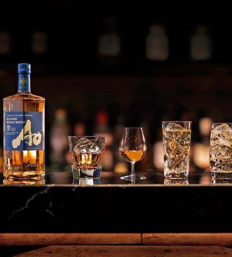 A bottle of Japanese whisky on a bar alongside glasses of the spirit