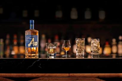 A bottle of Japanese whisky on a bar alongside glasses of the spirit