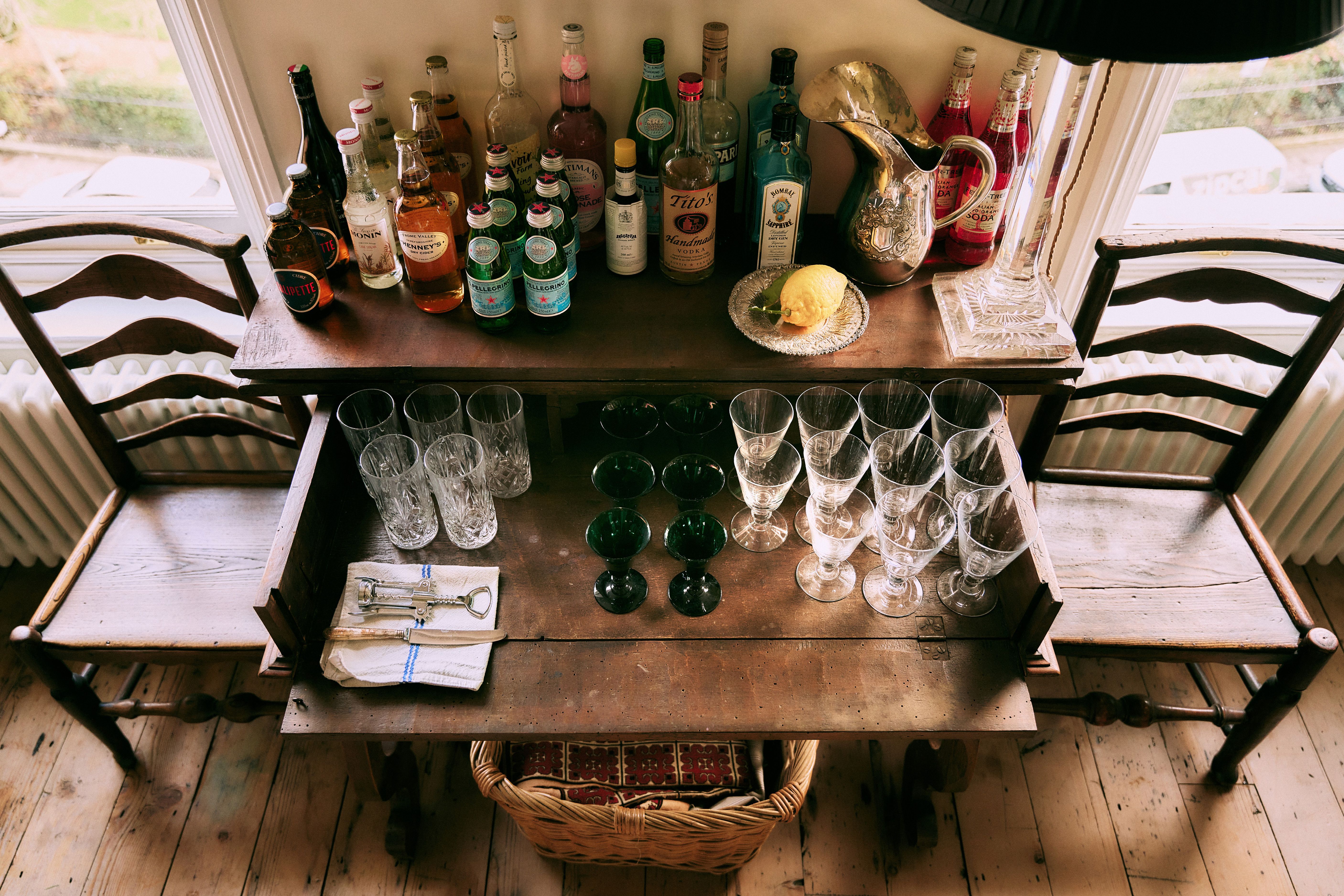 Drinks table with bottles and antique glassware in Jamie Sharp’s home