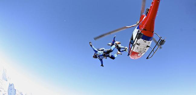 two sky divers jump out of a helicopter