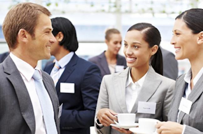 Two businesswomen with coffee speak to a handsome businessman at a conference. Horizontal shot.