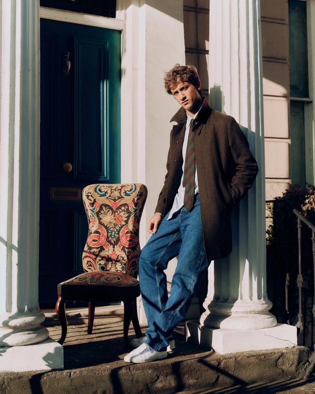 Jamie Sharp standing in a doorway beside an upholstered antique chair