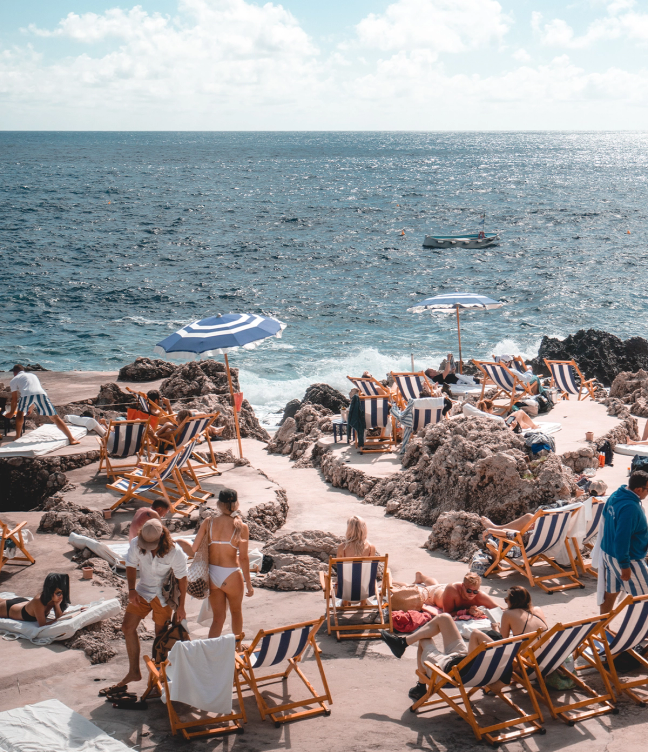 people on a rocky Beach in Capri with striped deck chairs