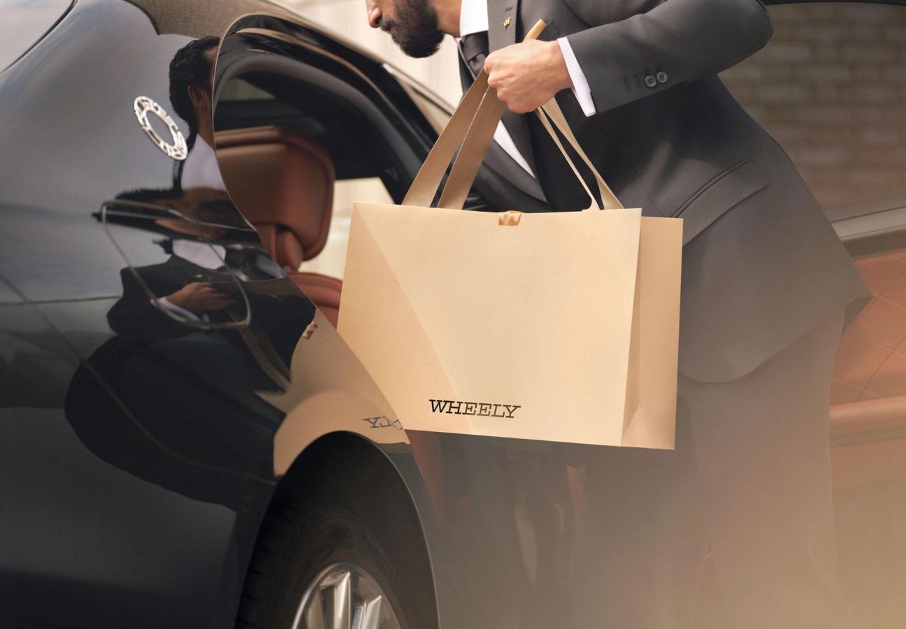Chauffeur removing Wheely gift bag from passenger seat of car
