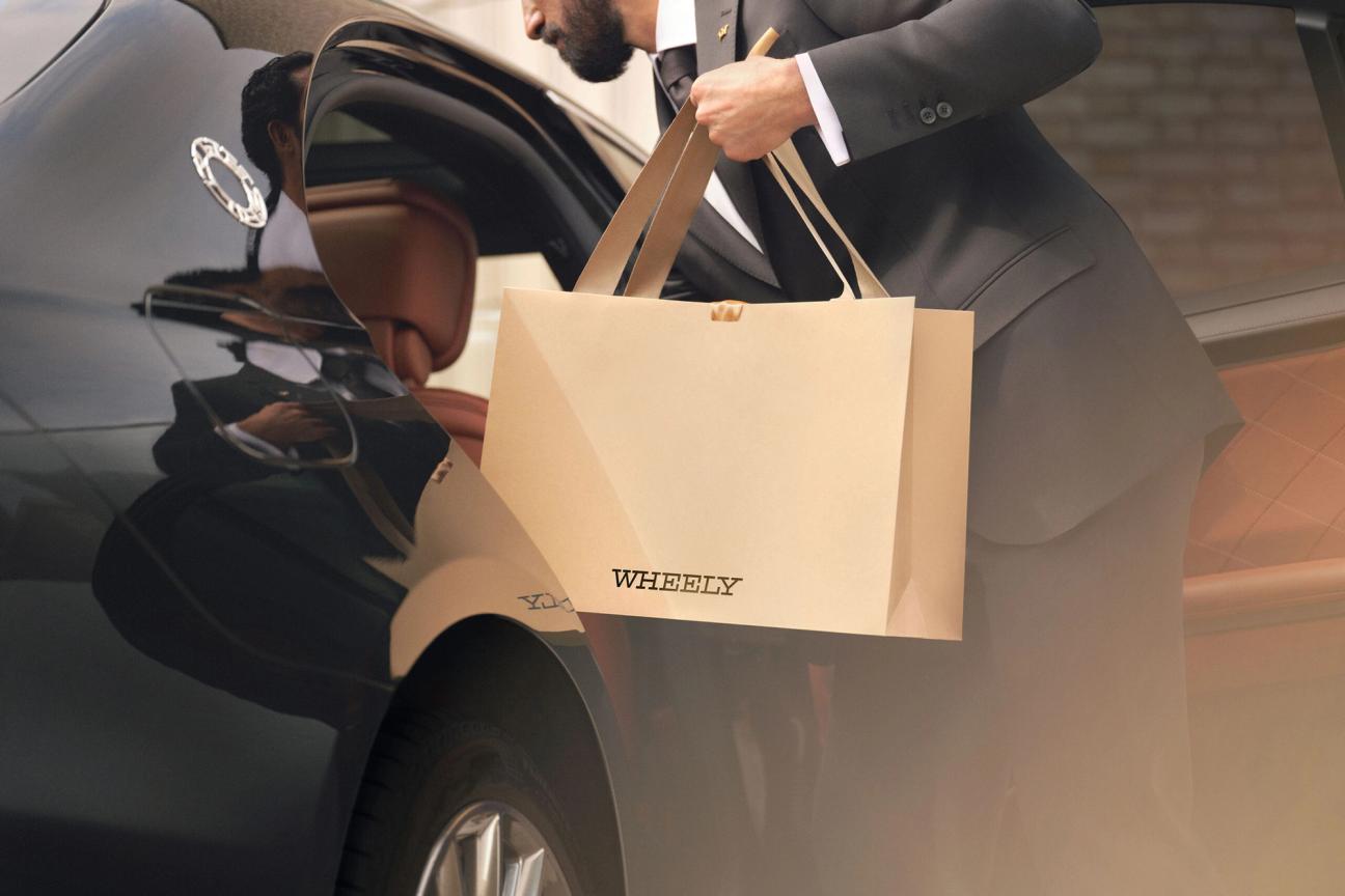 Chauffeur removing Wheely gift bag from passenger seat of car