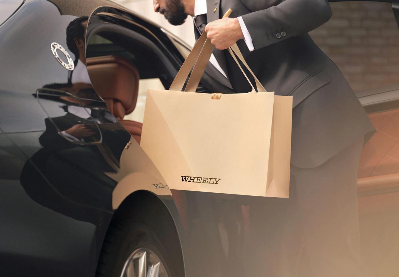 Chauffeur removing Wheely gift bag from passenger seat of car