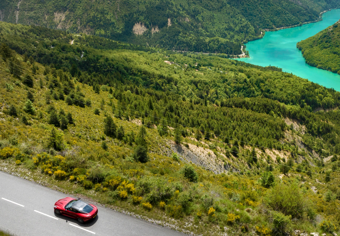 Red Aston Martin DB12 driving on the road