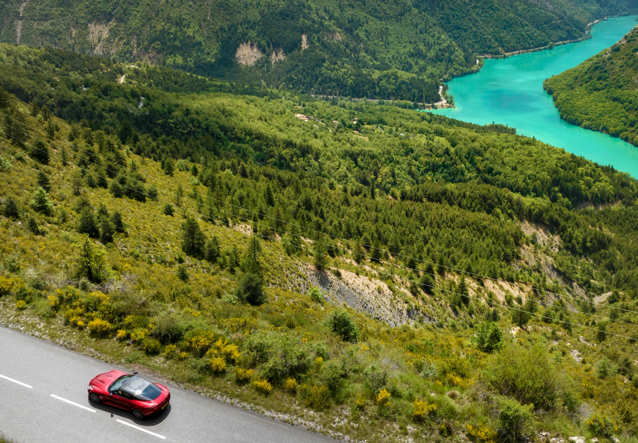 Red Aston Martin DB12 driving on the road
