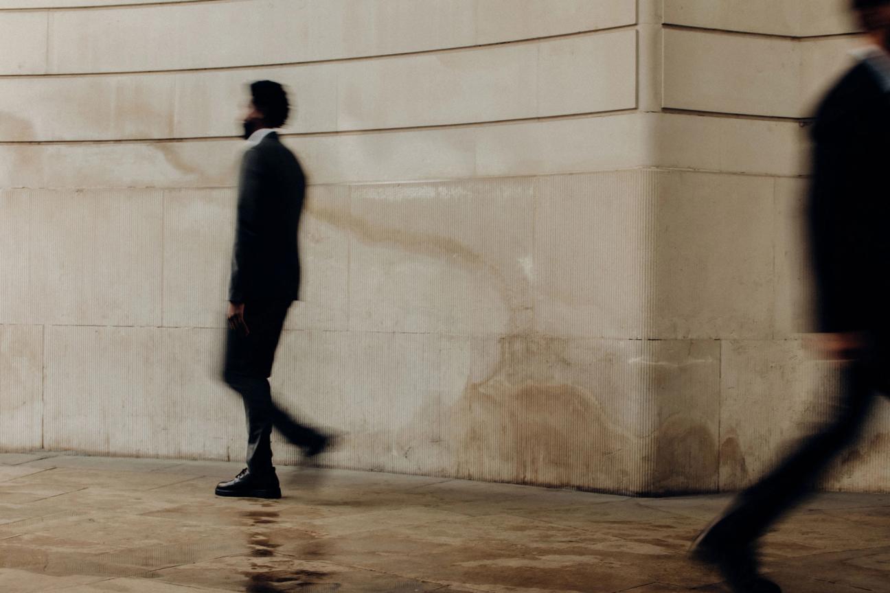 man walking past building with motion blur