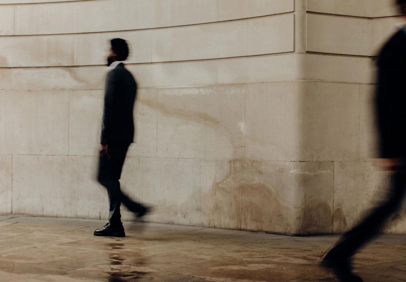 man walking past building with motion blur