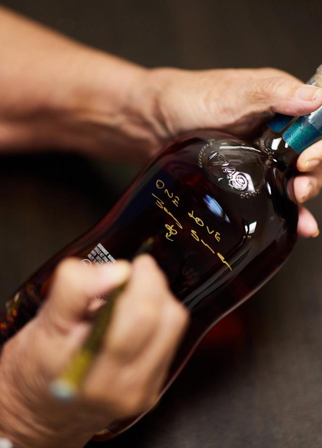 A person writing on an Appleton Estate rum bottle