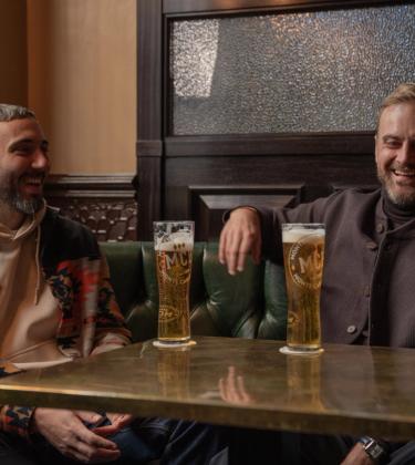 Two men sharing Monte Carlo Beer at a table