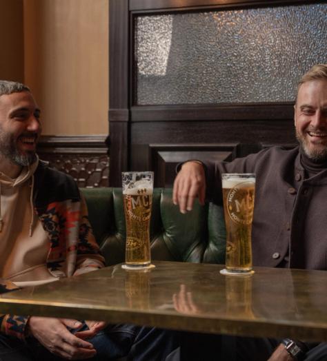 Two men sharing Monte Carlo Beer at a table
