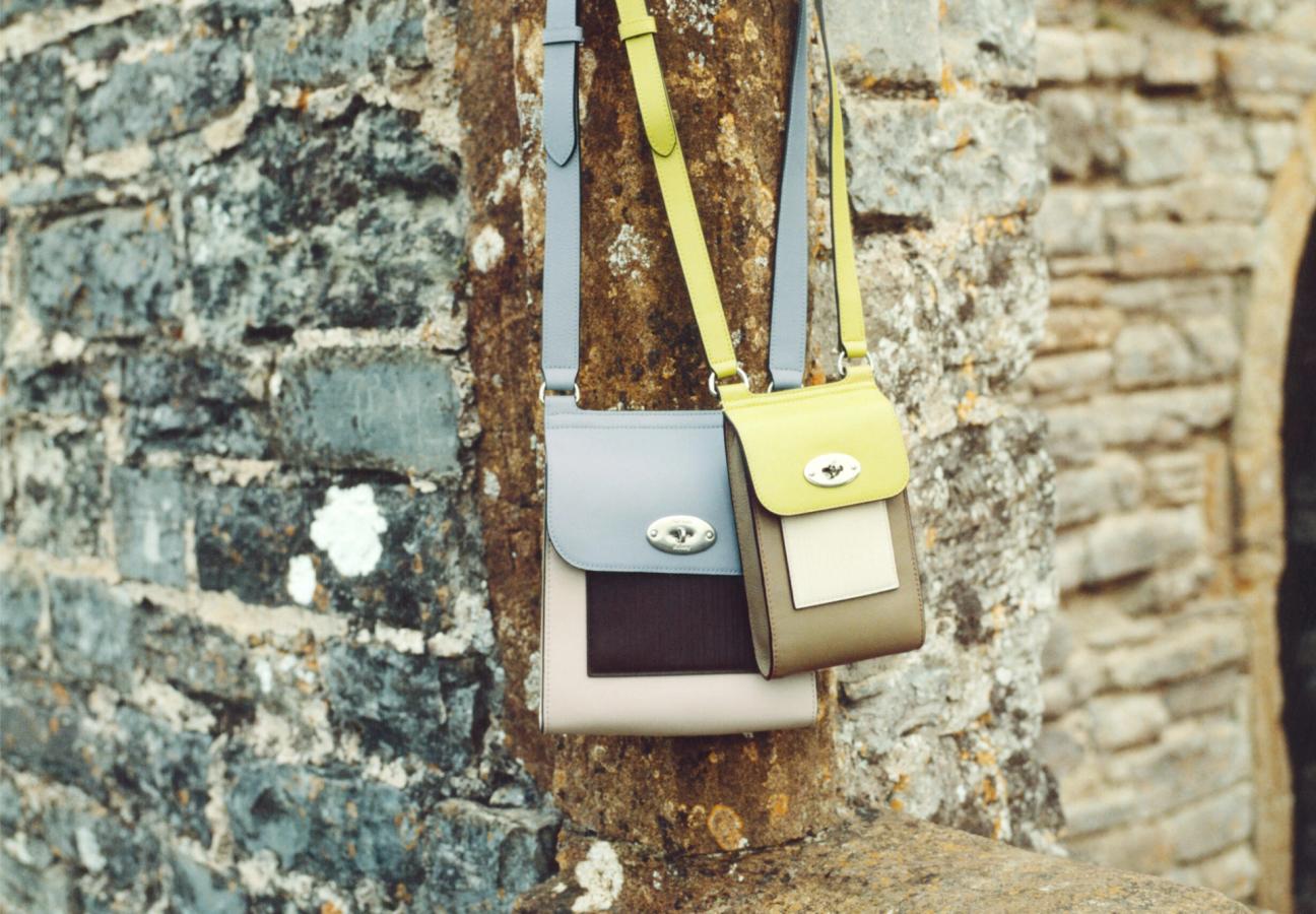Mulberry Antony bag and Mini Antony bag in Paul Smith colour combinations hanging on a stone brick wall