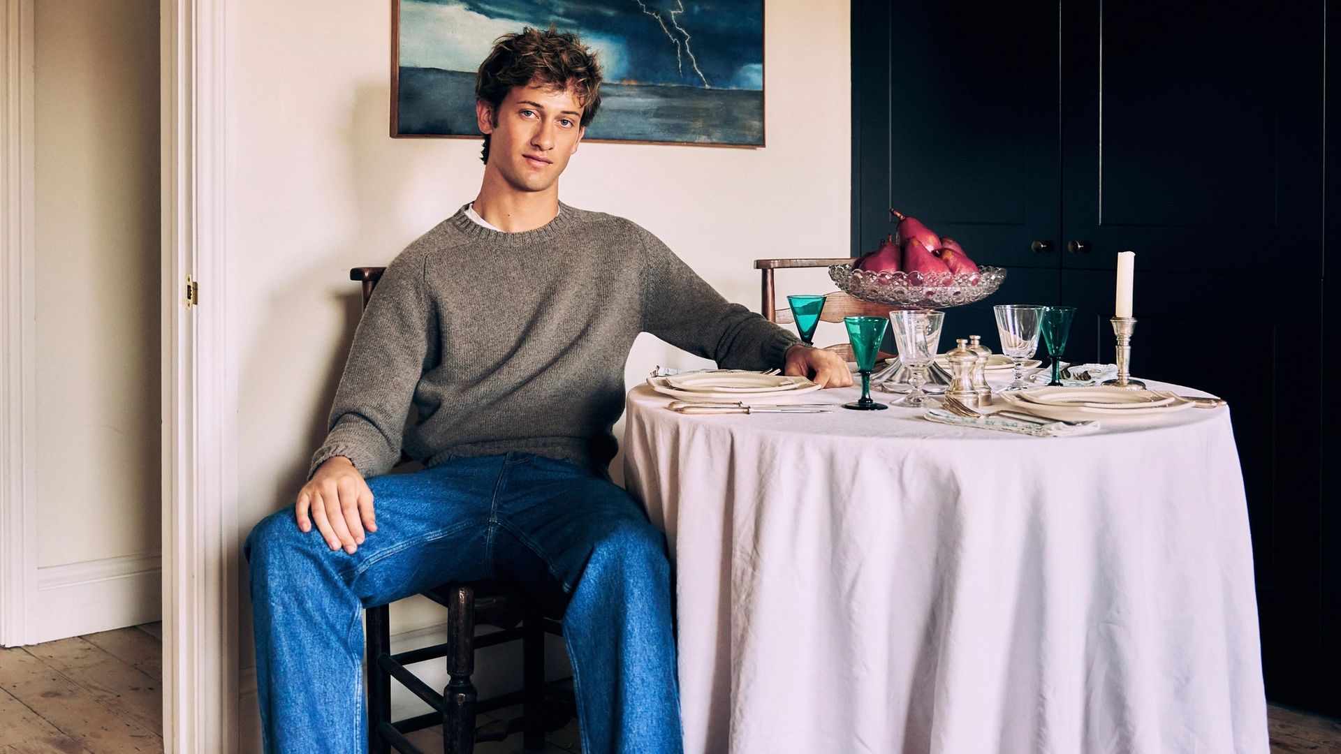 Jamie Sharp seated beside a table set with antique glassware