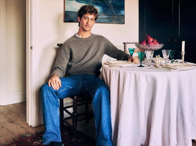 Jamie Sharp seated beside a table set with antique glassware