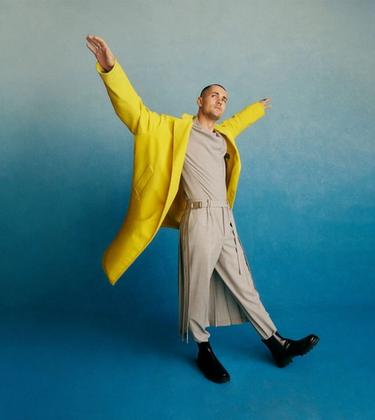 Jonah Hauer-King wearing a yellow jacket in front of a blue studio background