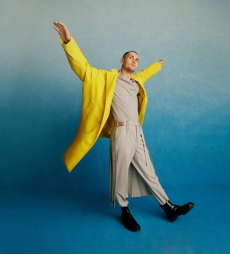 Jonah Hauer-King wearing a yellow jacket in front of a blue studio background