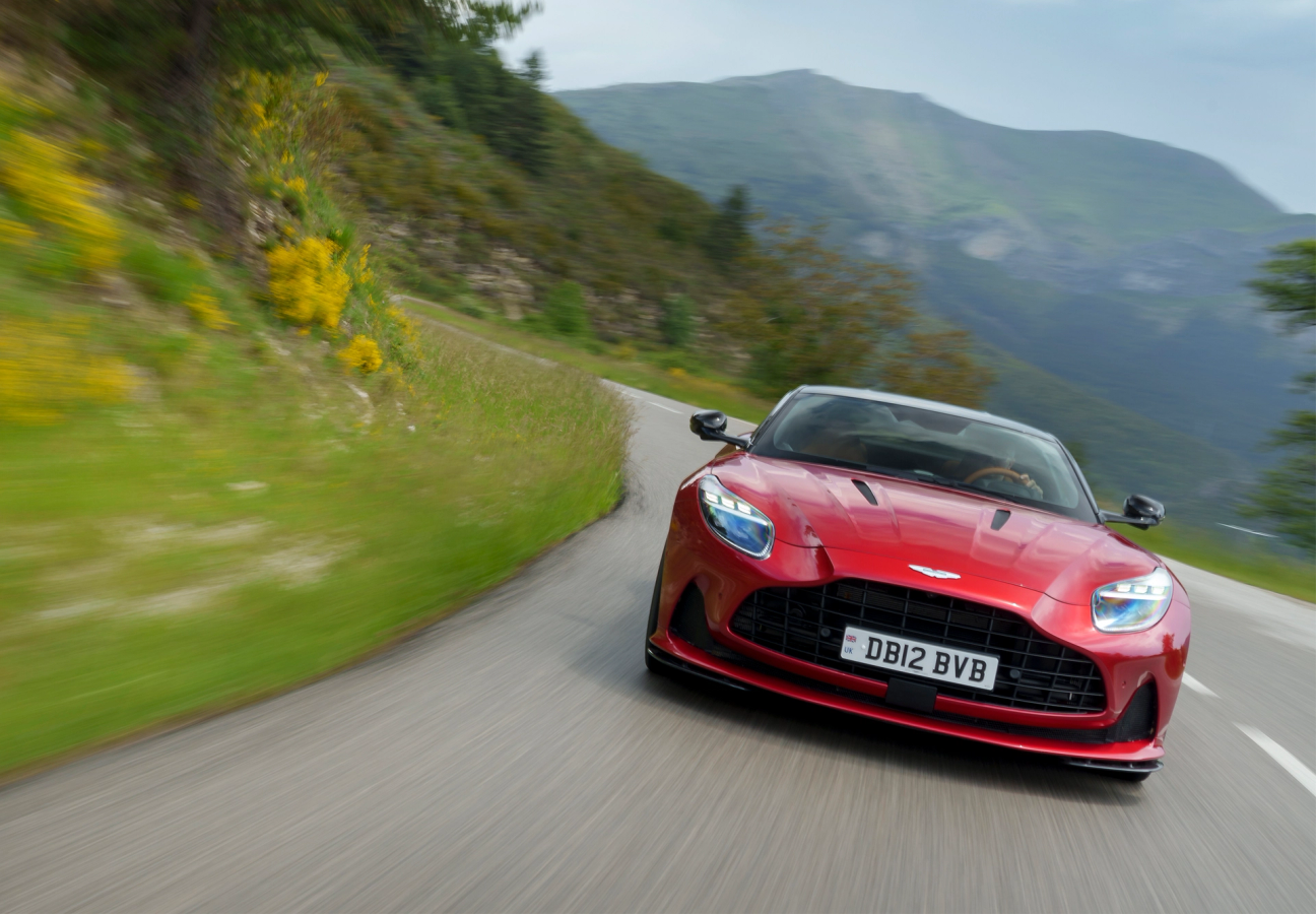Red Aston Martin DB12 driving on the road