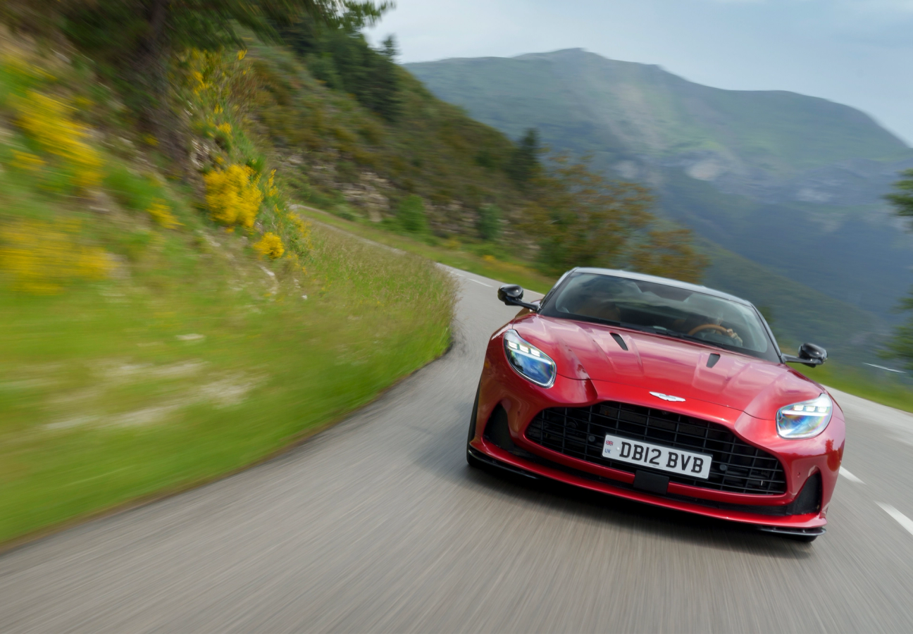 Red Aston Martin DB12 driving on the road