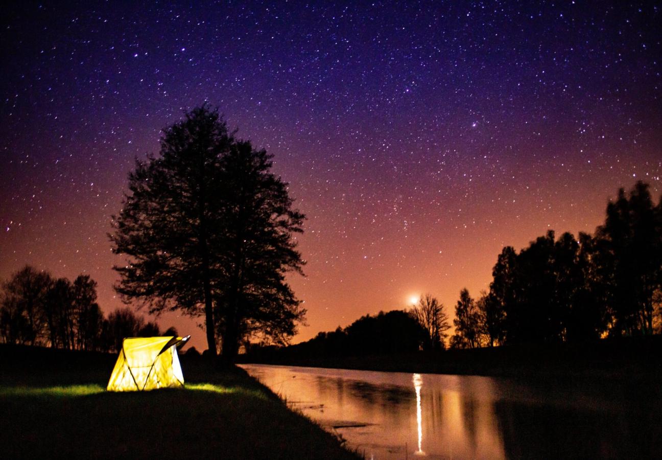 tent glows under stars and night sky while camping