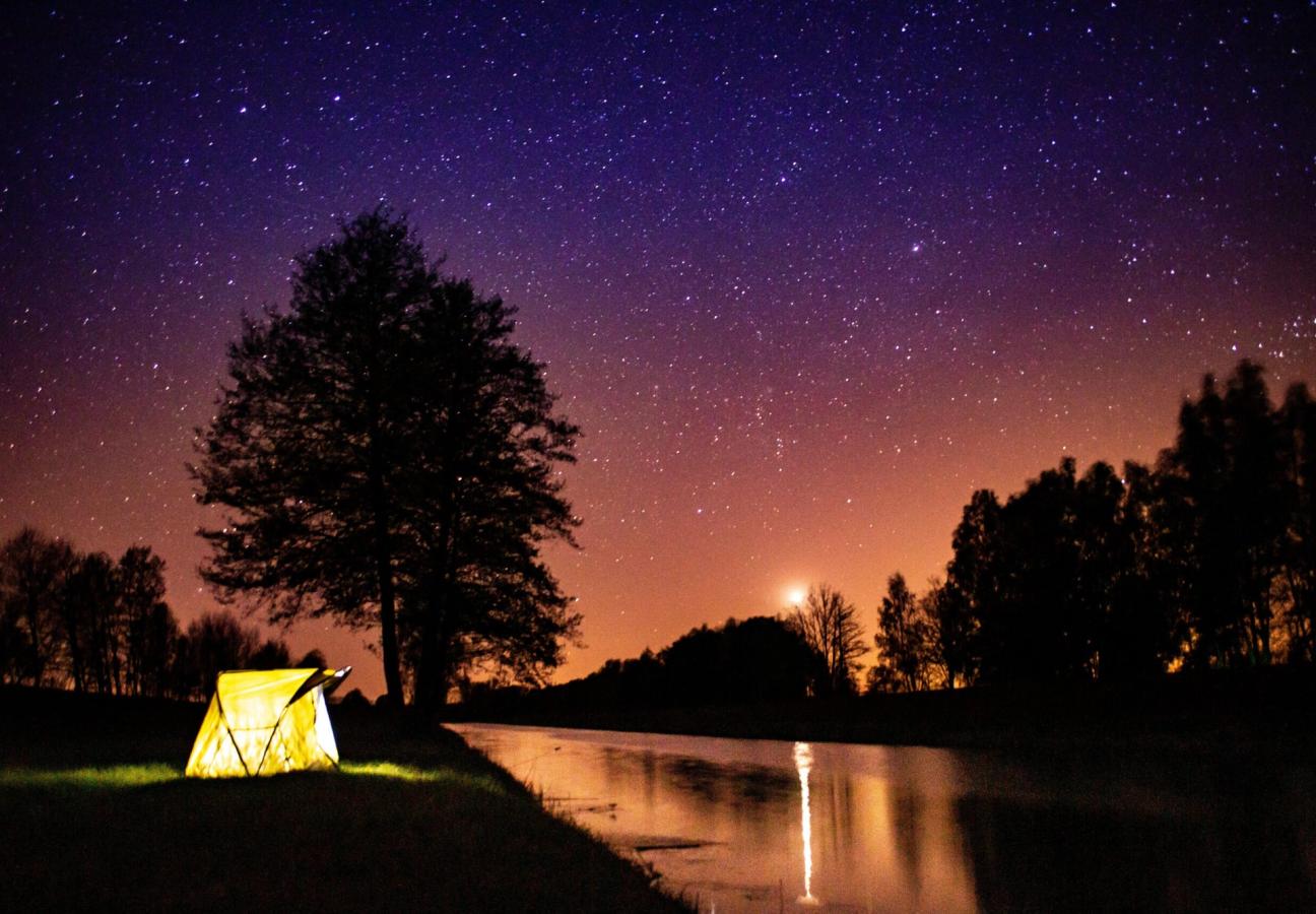 tent glows under stars and night sky while camping