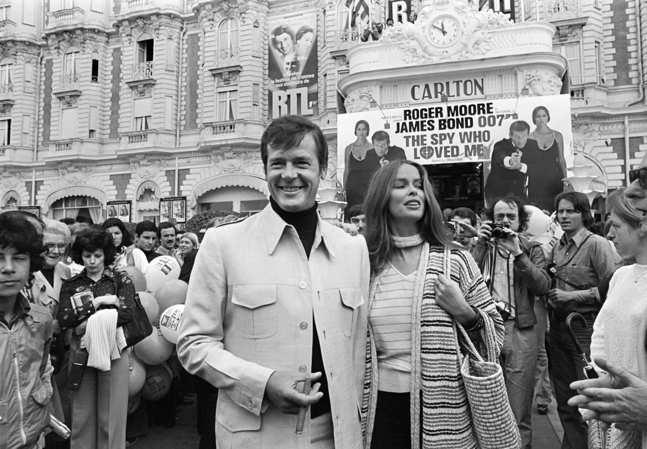 British actor Roger Moore and US actress Barbara Bach pose outside the Carlton Hotel for the presentation of the film "The spy who loved me" during the 30th Cannes Film Festival in Cannes, on May 20, 1977. (Photo by - / AFP) (Photo credit should read -/AFP via Getty Images)