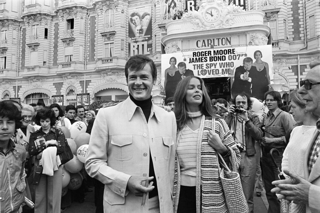 British actor Roger Moore and US actress Barbara Bach pose outside the Carlton Hotel for the presentation of the film "The spy who loved me" during the 30th Cannes Film Festival in Cannes, on May 20, 1977. (Photo by - / AFP) (Photo credit should read -/AFP via Getty Images)