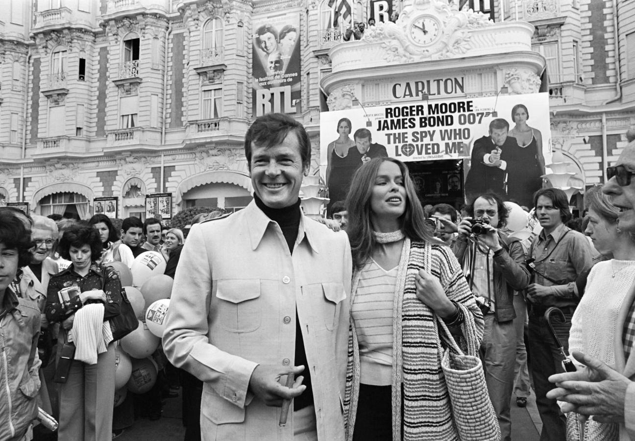 British actor Roger Moore and US actress Barbara Bach pose outside the Carlton Hotel for the presentation of the film "The spy who loved me" during the 30th Cannes Film Festival in Cannes, on May 20, 1977. (Photo by - / AFP) (Photo credit should read -/AFP via Getty Images)