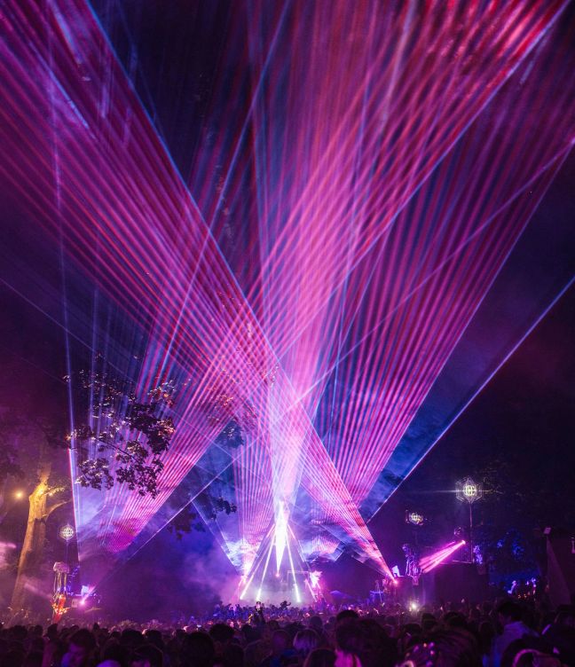 A purple and pink laser light show beaming across the sky at Wilderness Festival