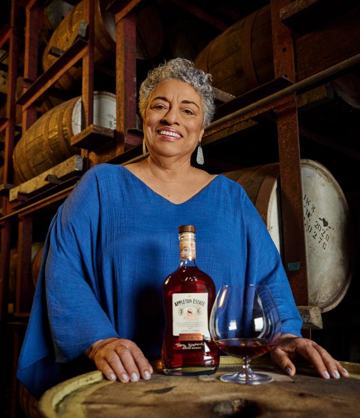 Joy Spence, master blender at Appleton Estate, standing next to a glass of rum