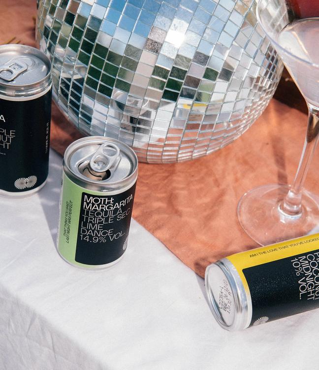 MOTH cans on a table at a party next to a disco ball