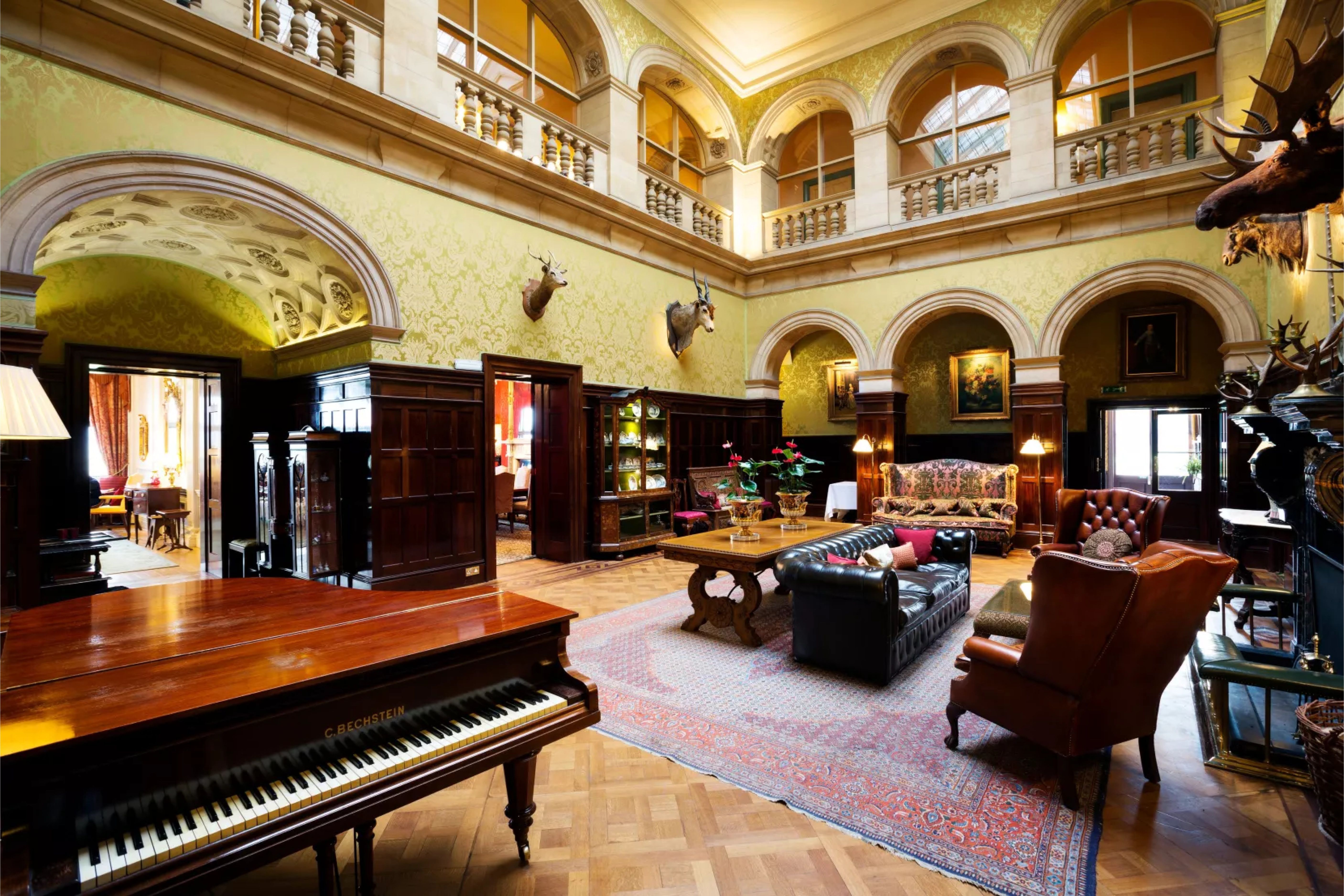 Double-height hall with galleries, arches and a grand piano at Stapleford Park
