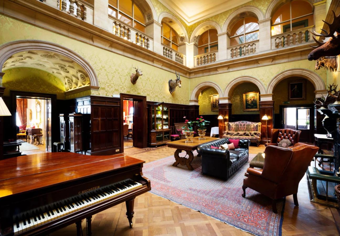 Double-height hall with galleries, arches and a grand piano at Stapleford Park