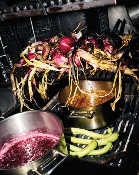 Assorted pots and pans filled with sauces, draped with onions and vegetables