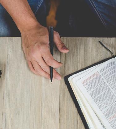 man wears a watch and holds a pen