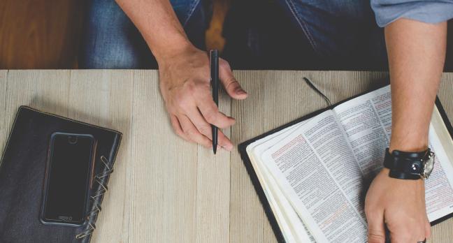 man wears a watch and holds a pen