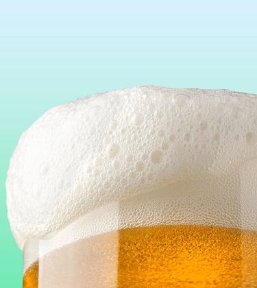 Glass of beer with foam falling over edge