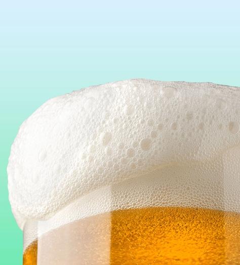 Glass of beer with foam falling over edge