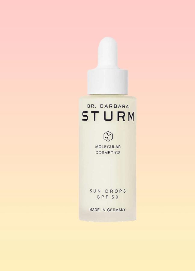 Dr. Barbara Sturm Sun Drops SPF50 bottle on a pink and yellow background
