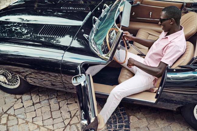 Man stepping out of a classic car in light pink Mr Marvis trousers