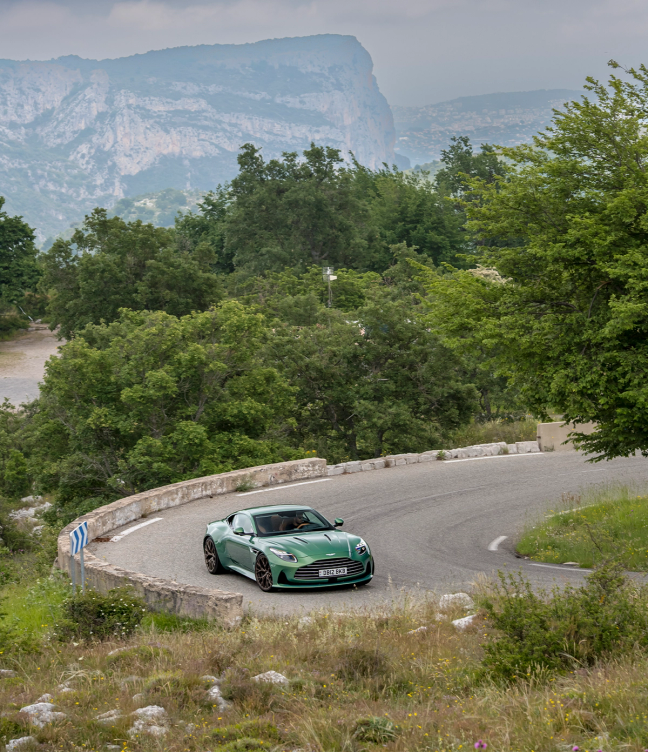 Green Aston Martin DB12 driving on the road