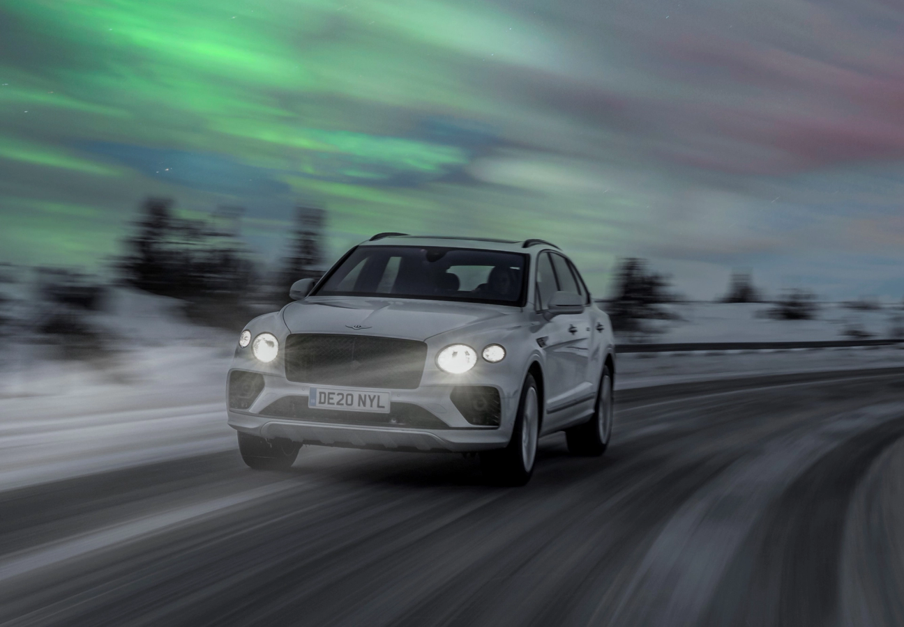 Bentley Bentayga driving through an icy road dimly lit by the northern lights