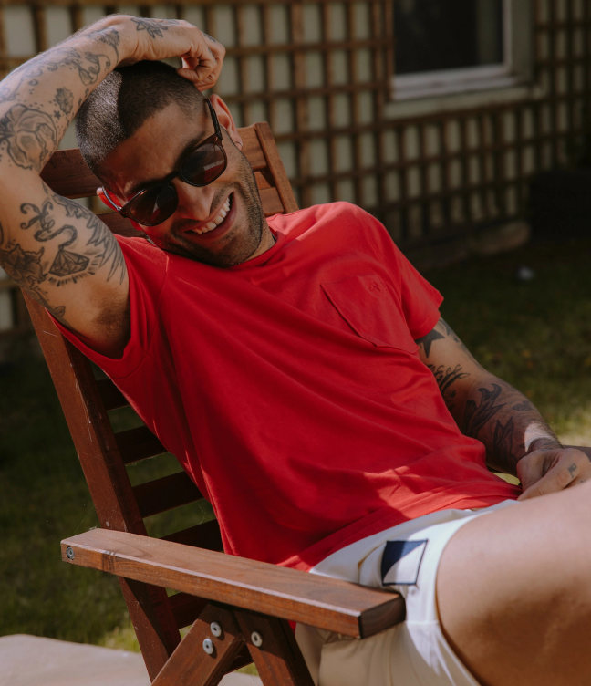 Tracksmith model, wearing a Tracksmith t-shirt and sitting on a chair