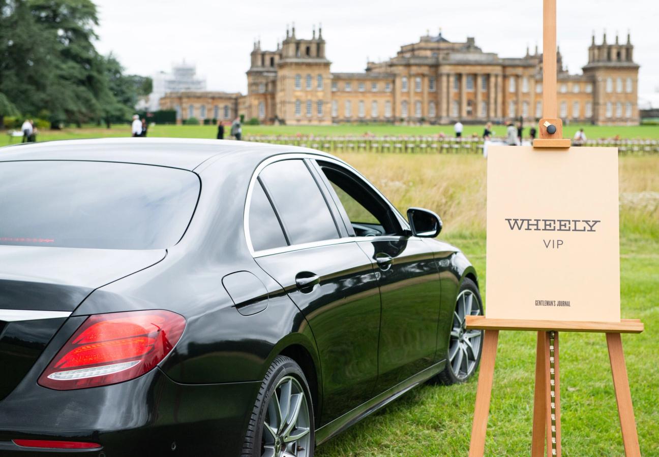 Car parked on a field next to a sign saying "Wheely VIP" in front of Blenheim Palace