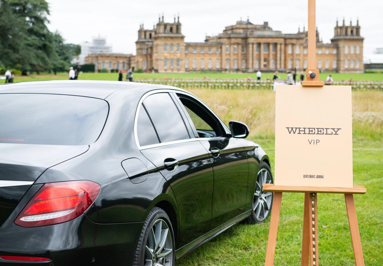 Car parked on a field next to a sign saying "Wheely VIP" in front of Blenheim Palace